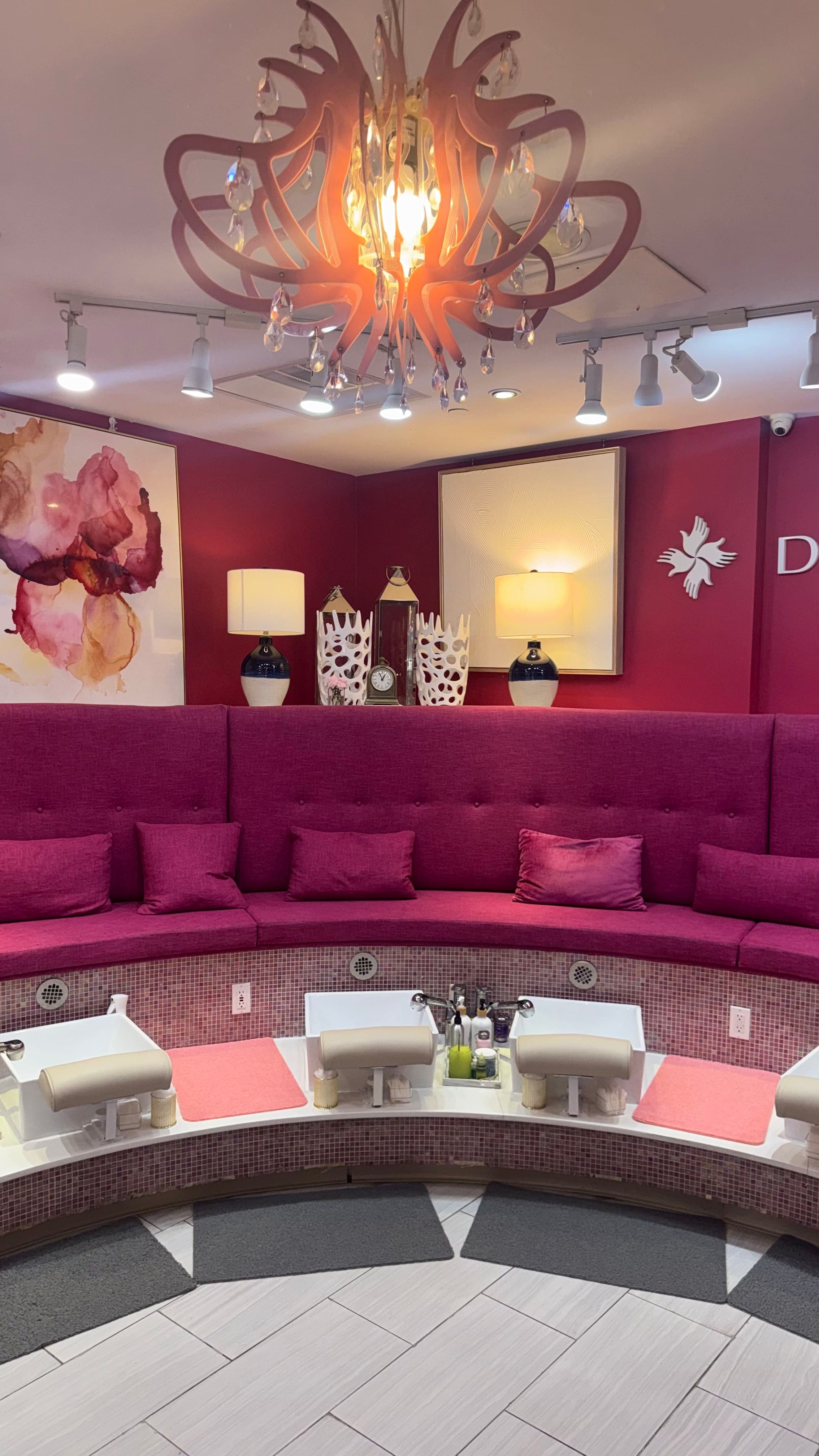 Pedicure lounge with cushioned curved seating and a chandelier